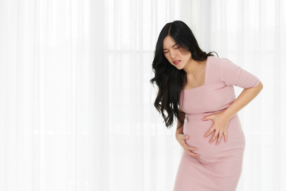 pregnant woman has a stomachache on window background